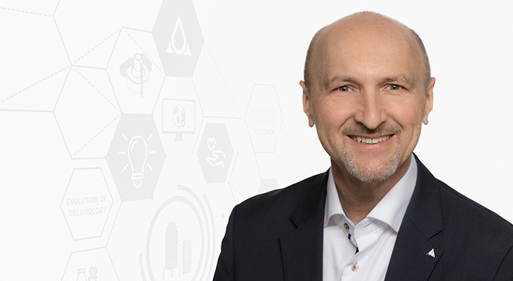 Portrait photo of Andreas Marchler, wearing a black blazer and a white shirt, smiling in front of a light background