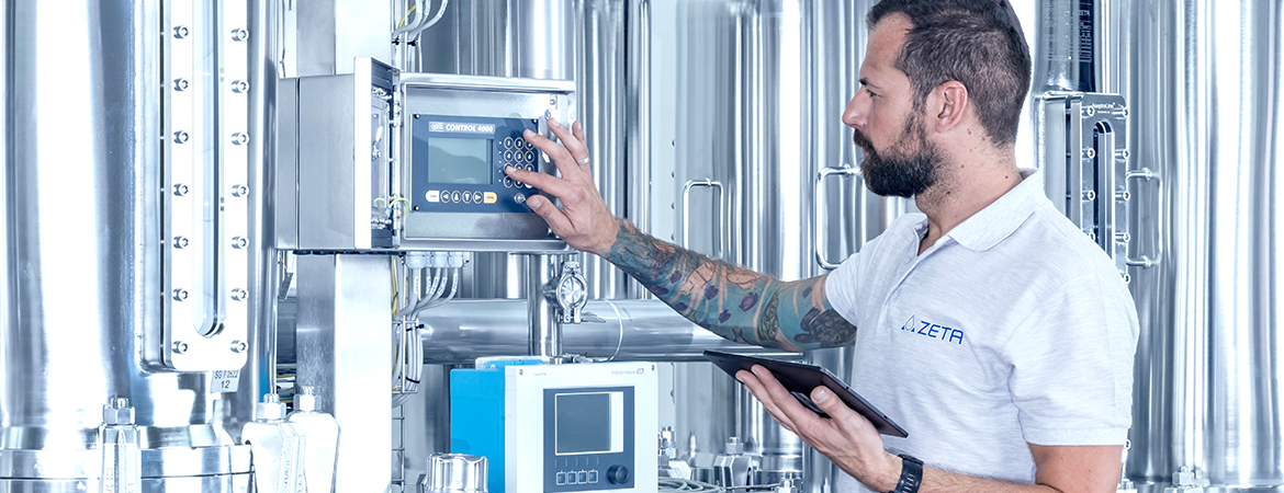 Person with tablet operating a small control screen in front of a production skid