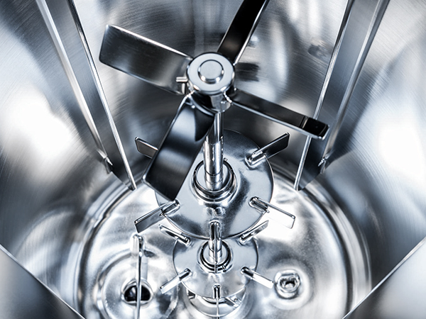 The image shows a close-up of a shiny metal mixer with a vertical shaft and several horizontal blades. It’s used in industrial settings to mix or blend materials, and the design looks precise and well-engineered.