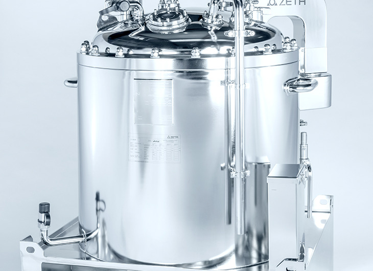 The image shows a shiny metal tank with pipes, valves, and gauges attached to the top. It’s mounted on a frame and labeled “ZETA.”