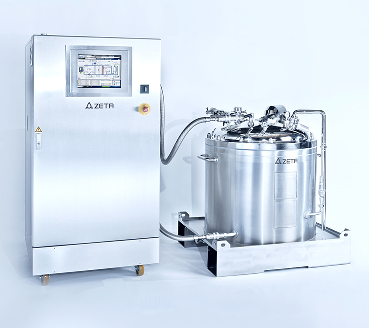 The image shows two pieces of industrial equipment made of shiny metal. One is a control unit with a screen and buttons, including an emergency stop. The other is a large tank with pipes and valves. Both are labeled “ZETA” and used in clean, precise manufacturing settings.