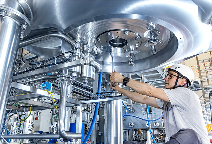 Person with protective gear performing installation work below the bottom of a large tank