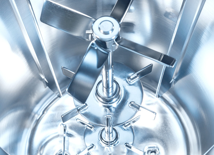The image shows a close-up of a shiny metal mixer with a vertical shaft and several horizontal blades. It’s used in industrial settings to mix or blend materials, and the design looks precise and well-engineered.