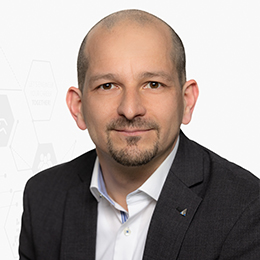 Portrait picture of a person wearing a white shirt and a black blazer in front of a light background.