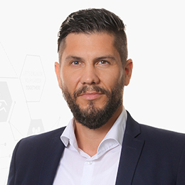 Portrait picture of a person wearing a white shirt and a black blazer in front of a light background.