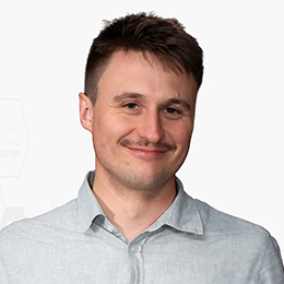 Portrait picture of a person wearing a grey shirt in front of a light background.