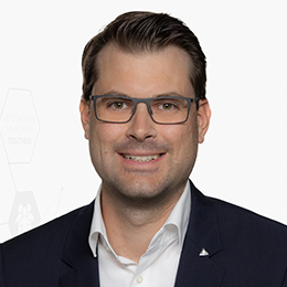 Portrait picture of a person wearing a white shirt and a black blazer in front of a light background.