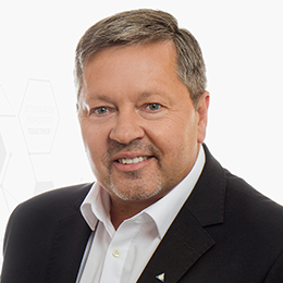 A portrait picture of a person wearing a white shirt and a black blazar in front of a light and neutral backgrounde
